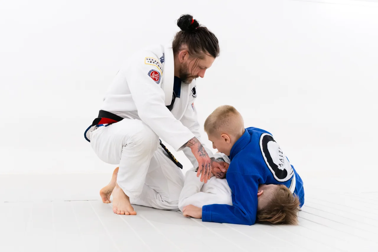 A coach helping young children practise on the mats at Kaizen Academy
