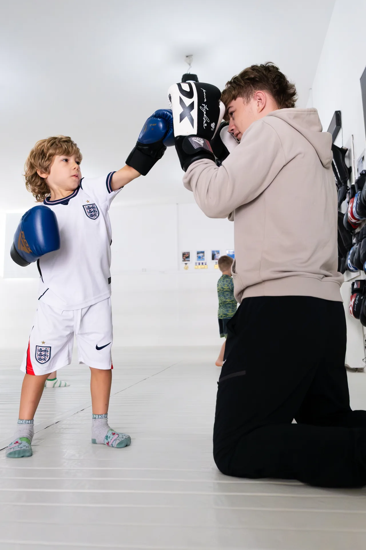 A Kaizen coach holding pads for a child during a kickboxing drill