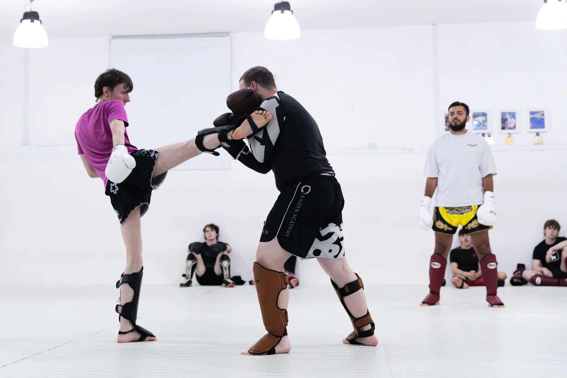Kickboxing partners practising a kick into a pad at Kaizen Academy
