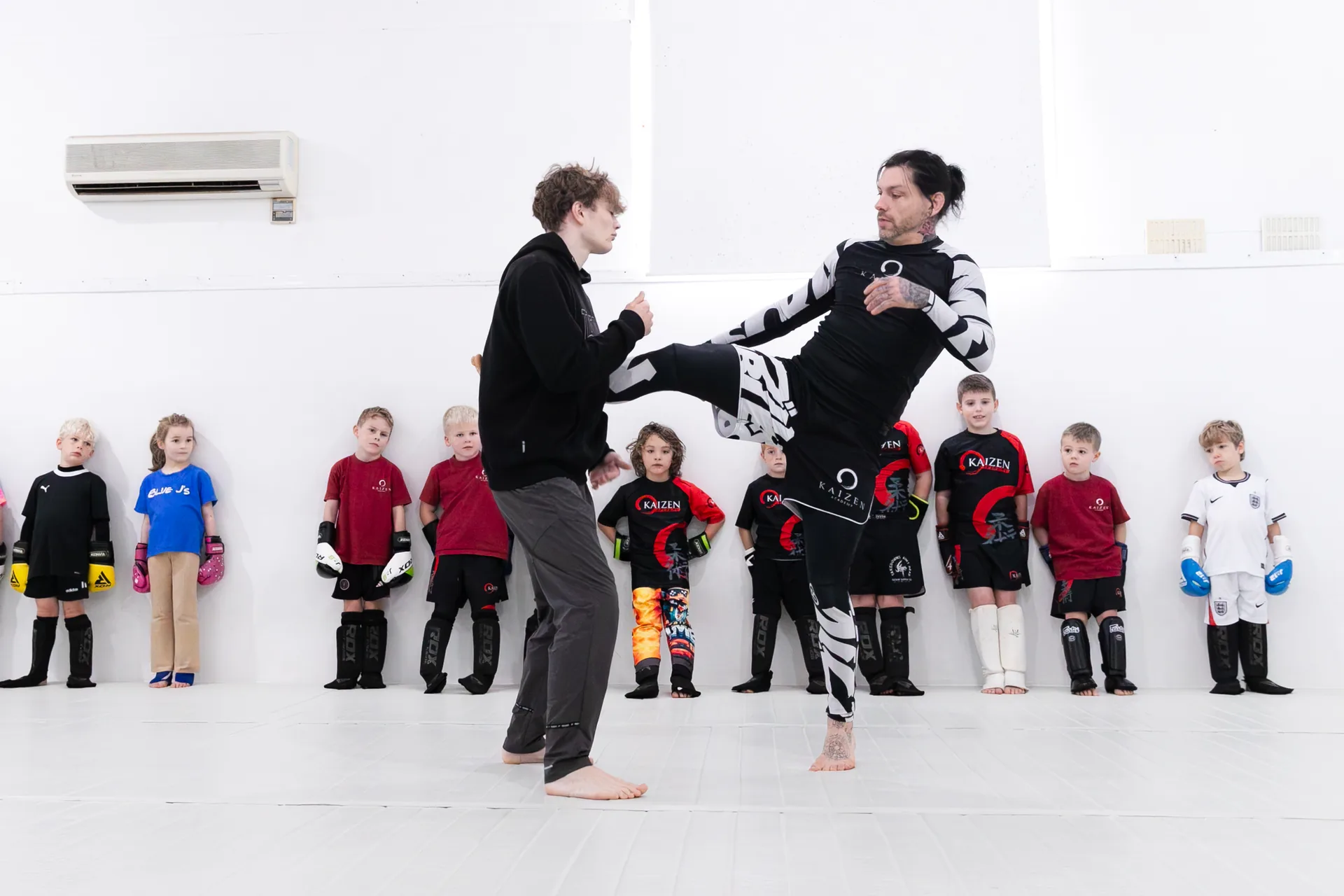 A Kaizen coach showing children a kickboxing technique during class